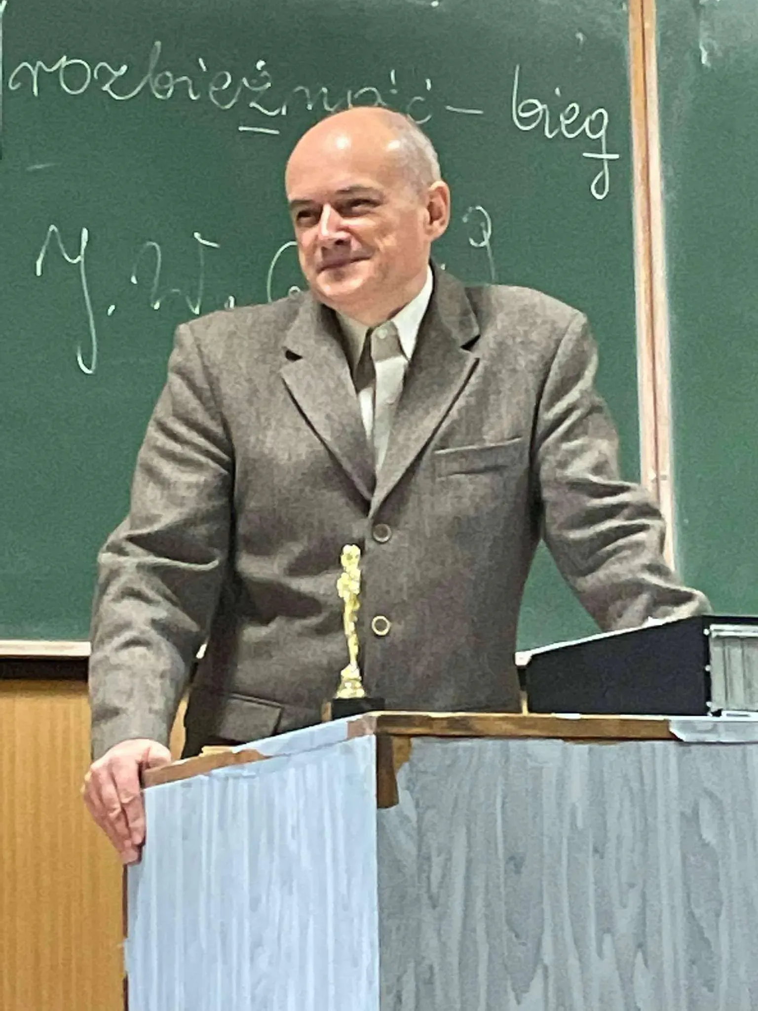 człowiek stojący na podium przed tablicą